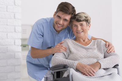 caregiver hugging senior woman sitting on the wheelchair smiling
